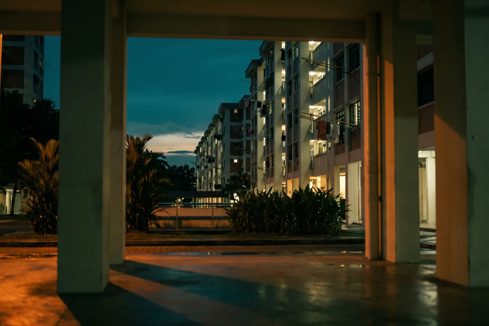 A Singapore housing block at dusk, seen from a void deck after rain
